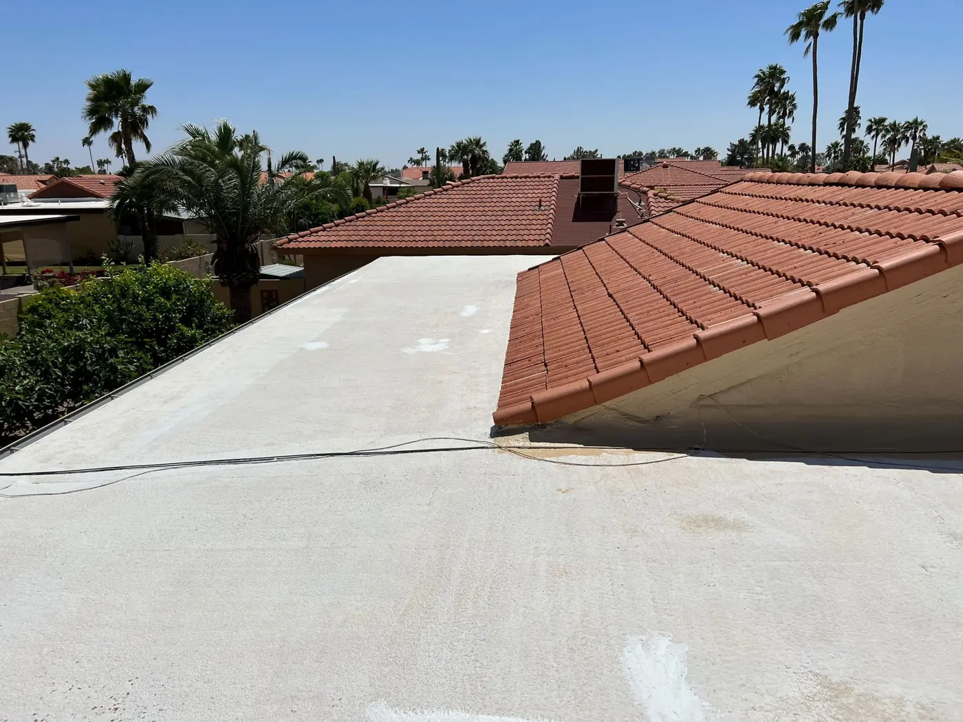 White coated flat roof next to a tile roof