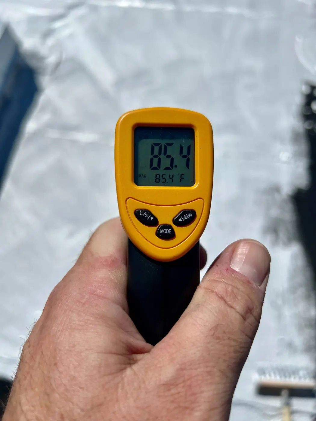 Infrared thermometer reading 85.4°F on the same roof after coating